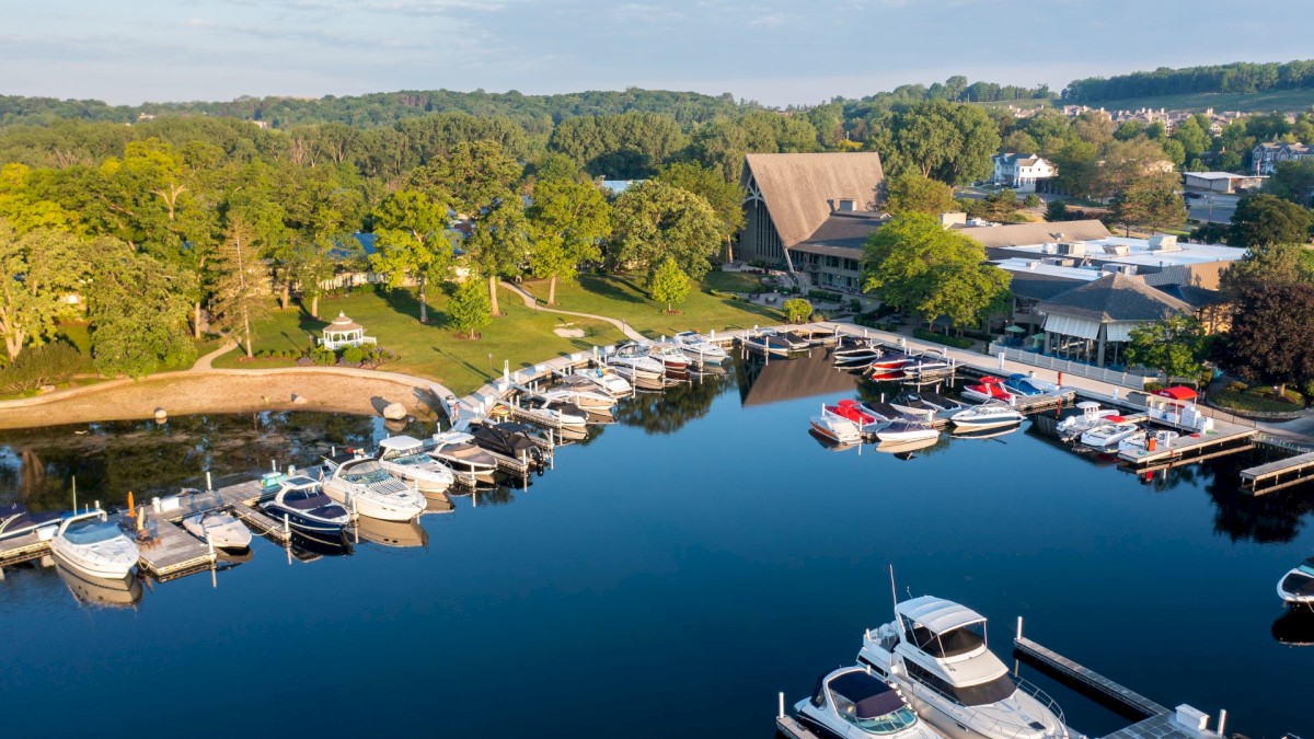 This image shows a marina with several boats docked, surrounded by greenery and buildings, under a clear sky.
